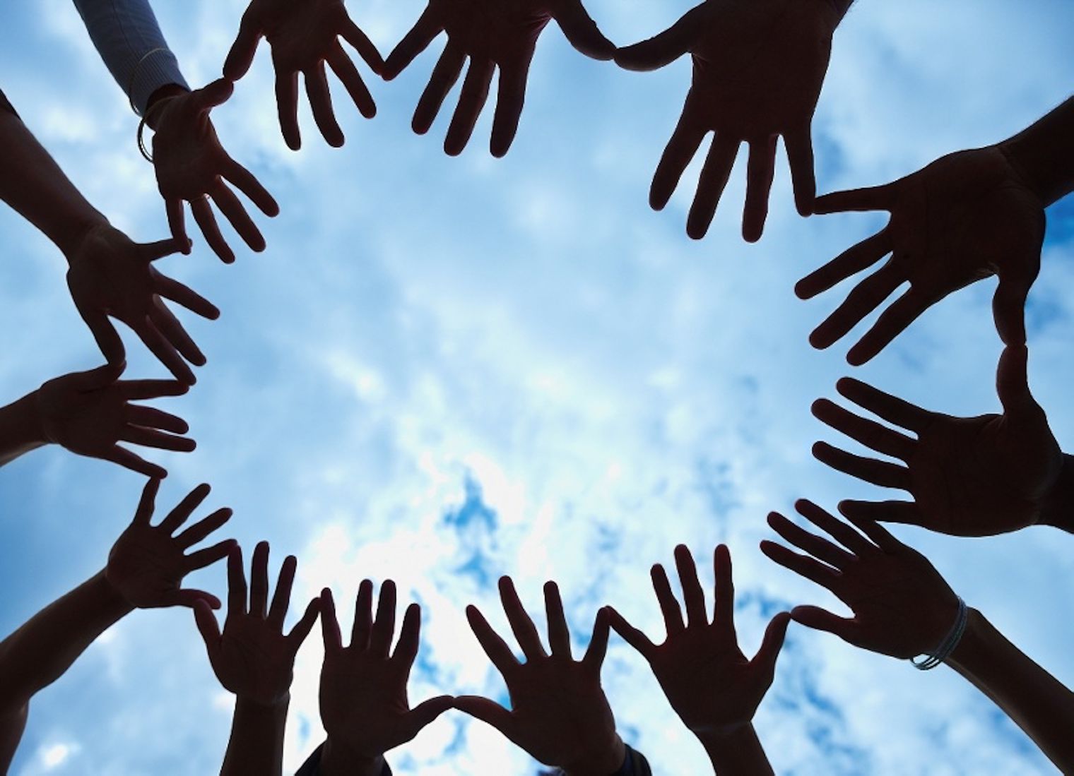 multiple hands with sky in background