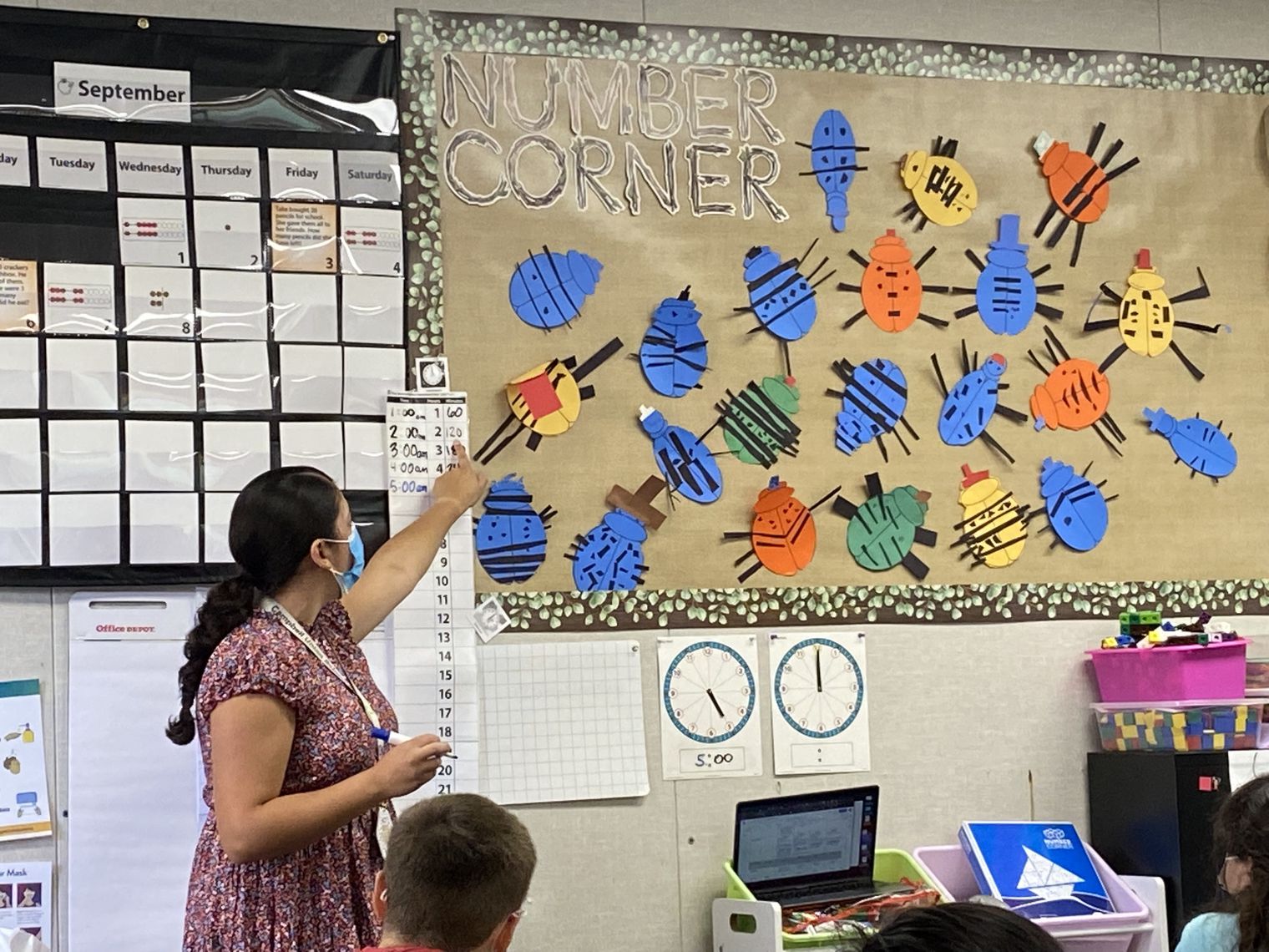 Teacher pointing to a math chart.