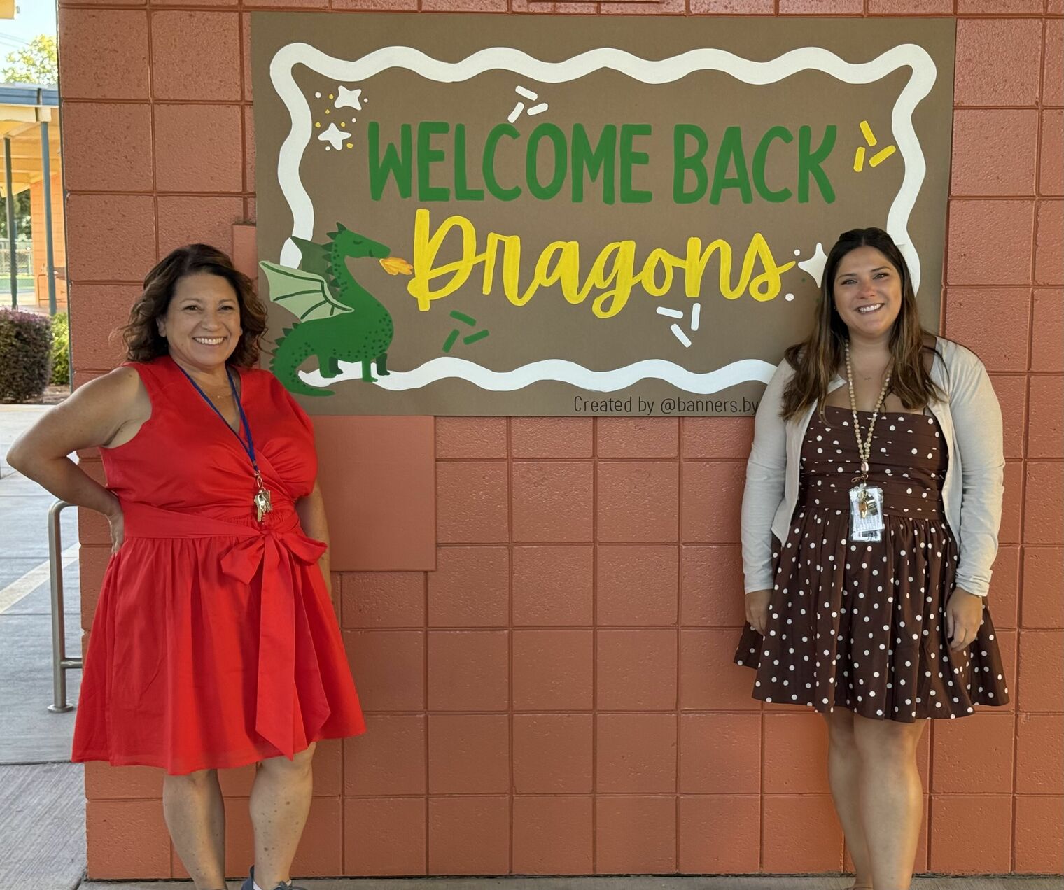 Two women standing front of a welcome back banner