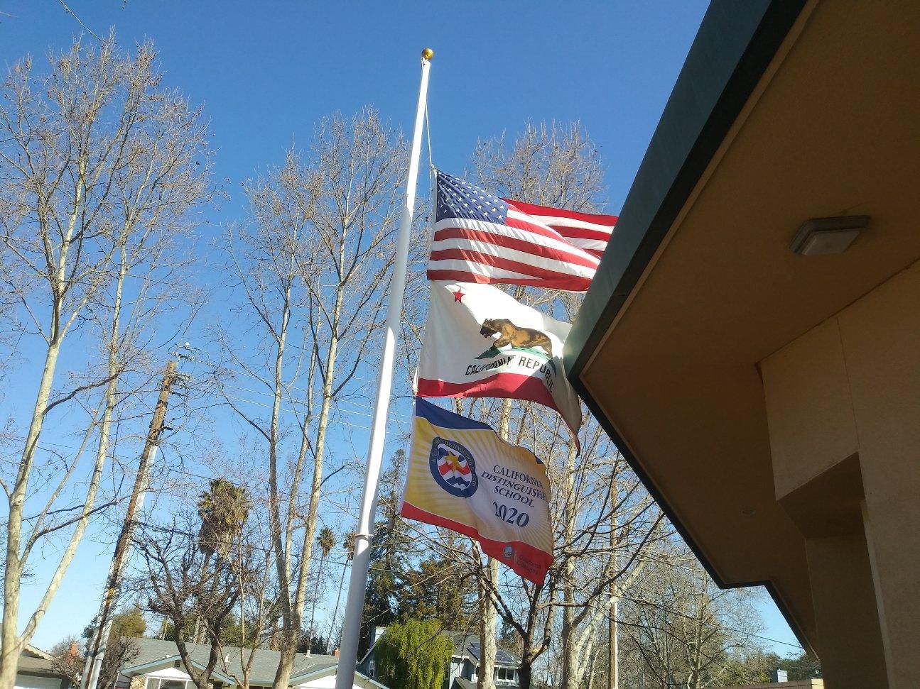 Three flags on a flag pole over Castlemont Elementary School