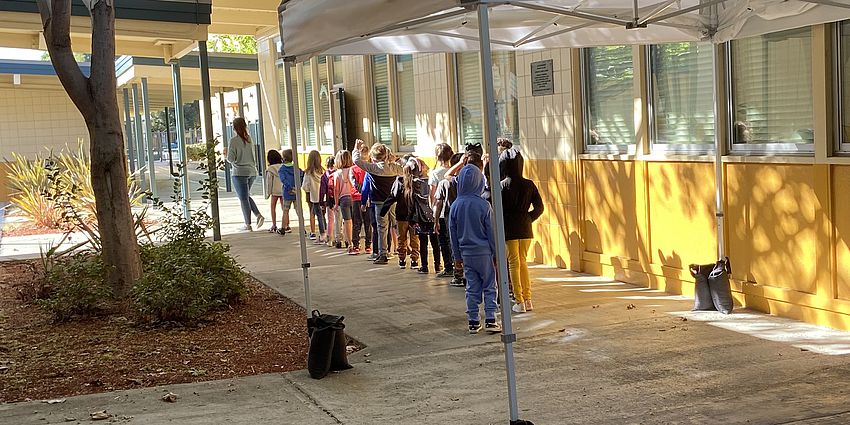 A line of students walking behind their teacher
