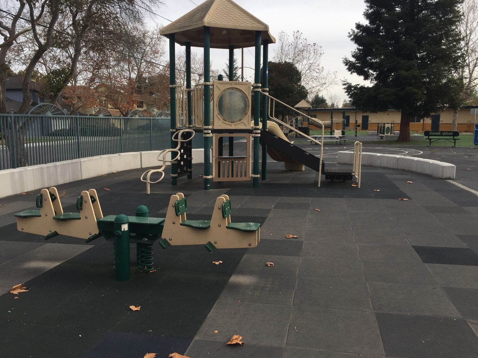Kindergarten playground equipment with classroom in the background