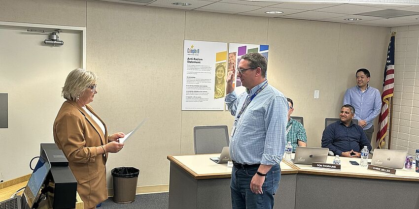 Area 5 trustee Sam Krow-Lucal is taking the oath of office. The oath is presented by Superintendent Viramontez and fellow board members are looking on.