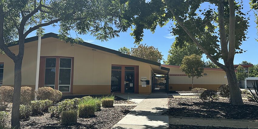 Photo of the front of Castlemont School including a building, sidewalks and trees