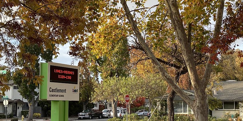 Castlemont school sign among autumn trees.
