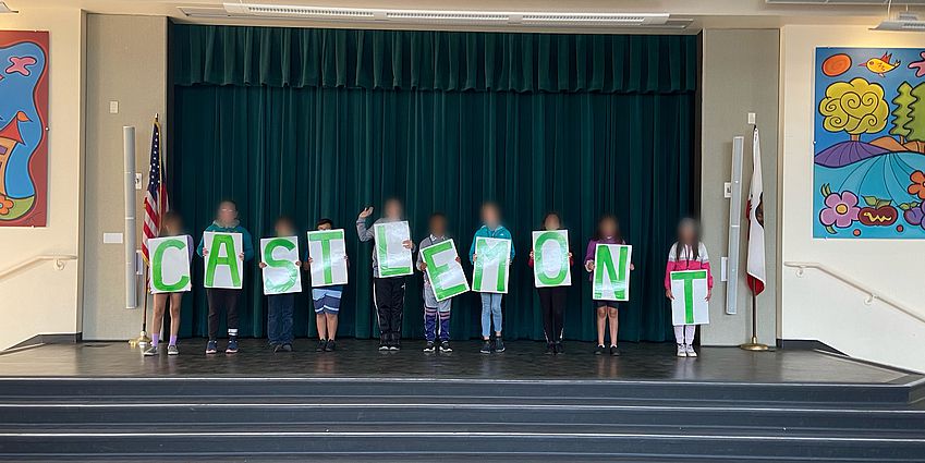 Elementary students holding letter signs spelling "Castlemont."