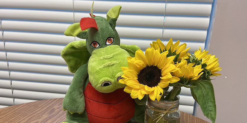 Dragon toy and sunflowers in a vase