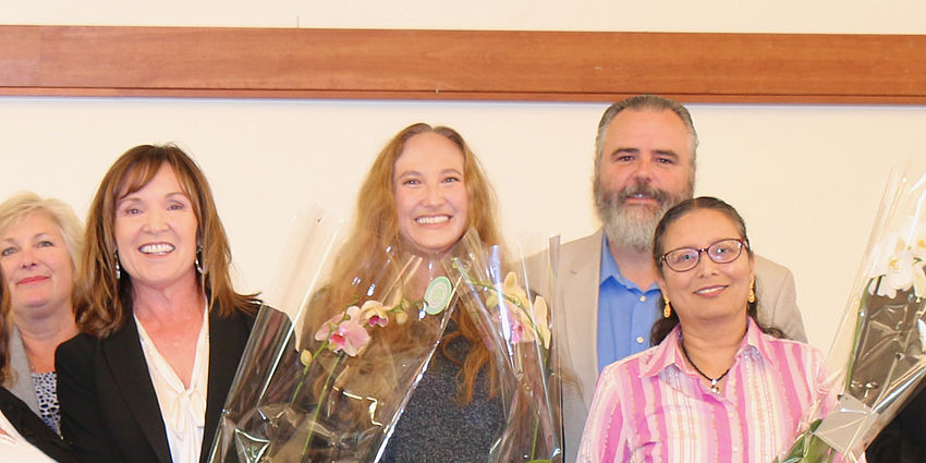 Four women holding orchids and one man.