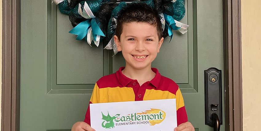 Boy holding Castlemont sign in front of a door.