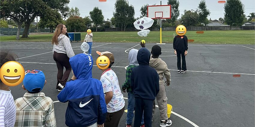 A line of elementary school students enthusiastically play a game on a playground.