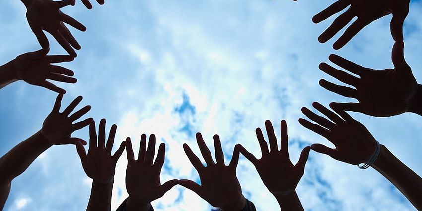 multiple hands with sky in background