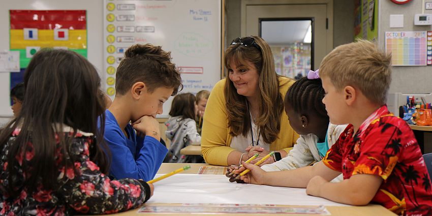 Teacher with four students at a table.