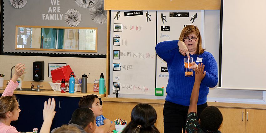 woman in front of students demonstrating lesson