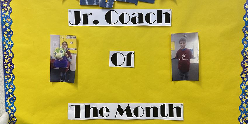 Two student photos displayed on Jr. Coach of the Month poster.