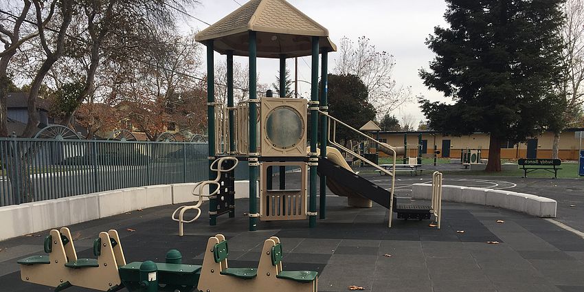 Kindergarten playground equipment with classroom in the background