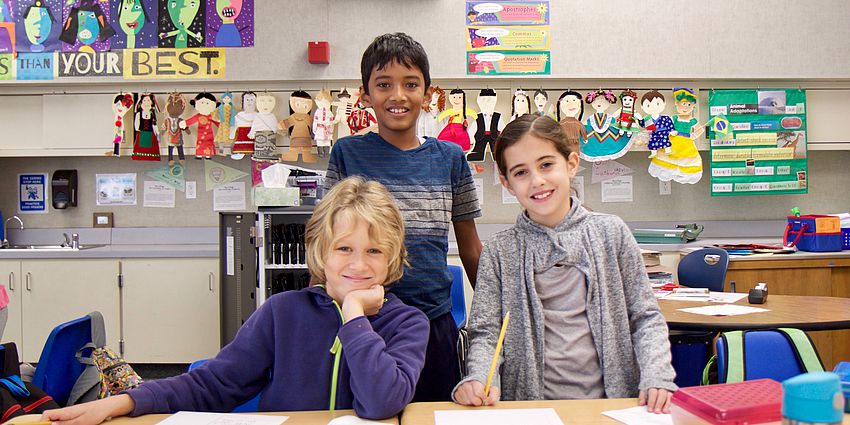 smiling students writing at a desk