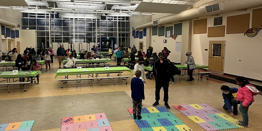 Families playing math games in a large room.