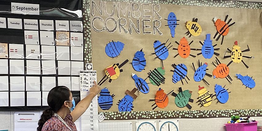 Teacher pointing to a math chart.