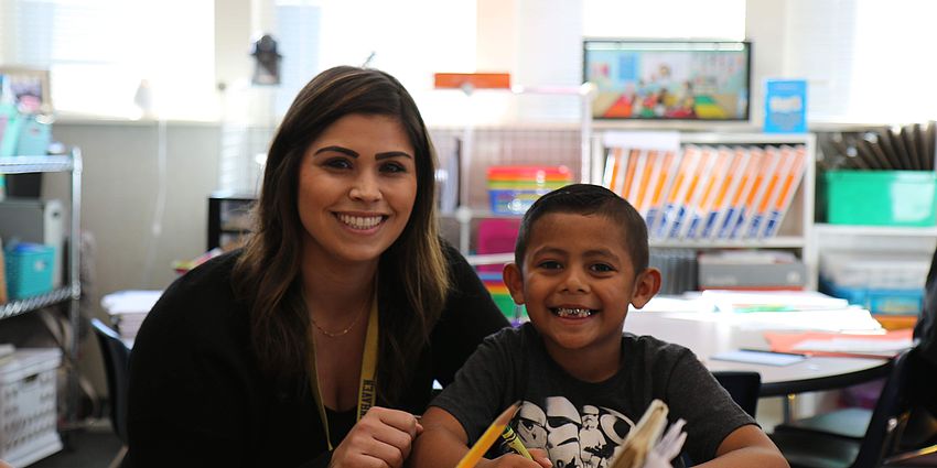 female teacher with young boy smiling at camera