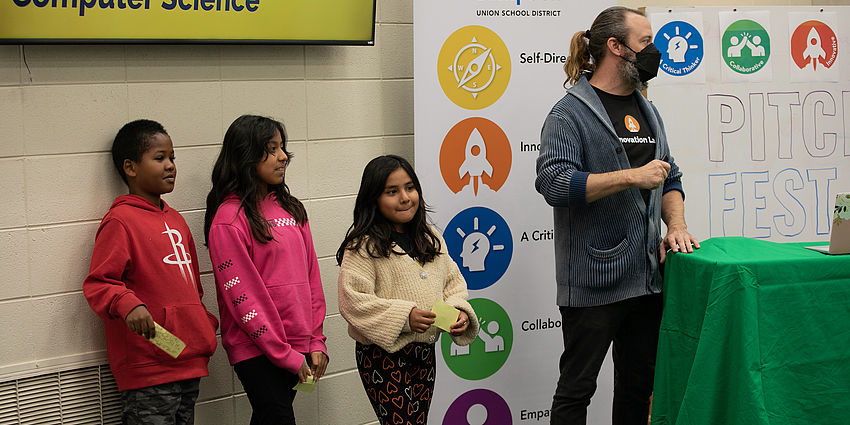 students and teacher standing and presenting to audience