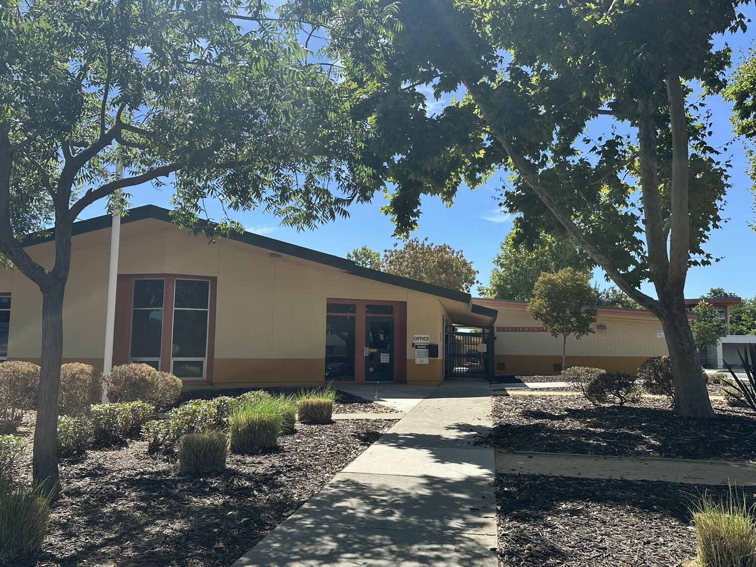Photo of the front of Castlemont School including a building, sidewalks and trees